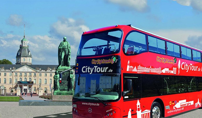 Karlsruhe CityTour Ein roter Doppeldeckerbus fährt am Schloss vorbei.